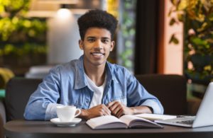 Cheerful black student doing homework at cafe